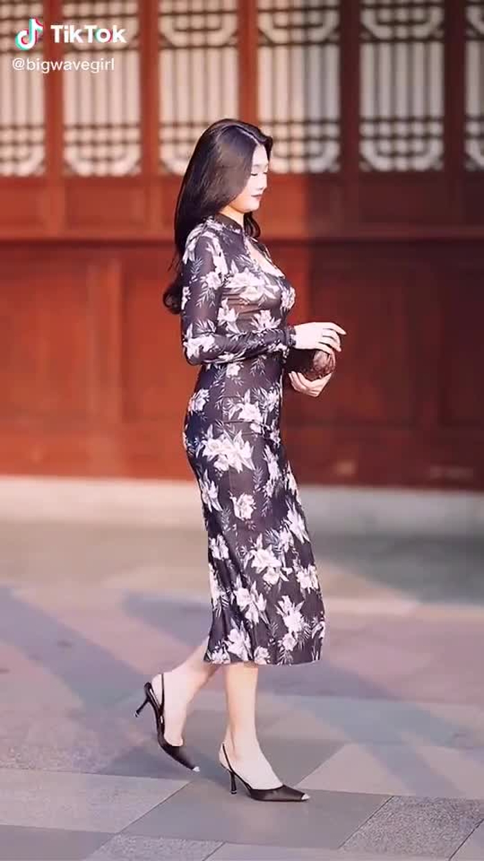 A woman wearing a cheongsam walking on the street is always a beautiful scenery.